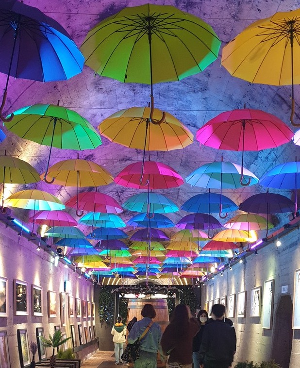 시민들이 와인동굴 내에 형형색색의 우산으로 장식된 길을 걷고 있다.  송희영 기자