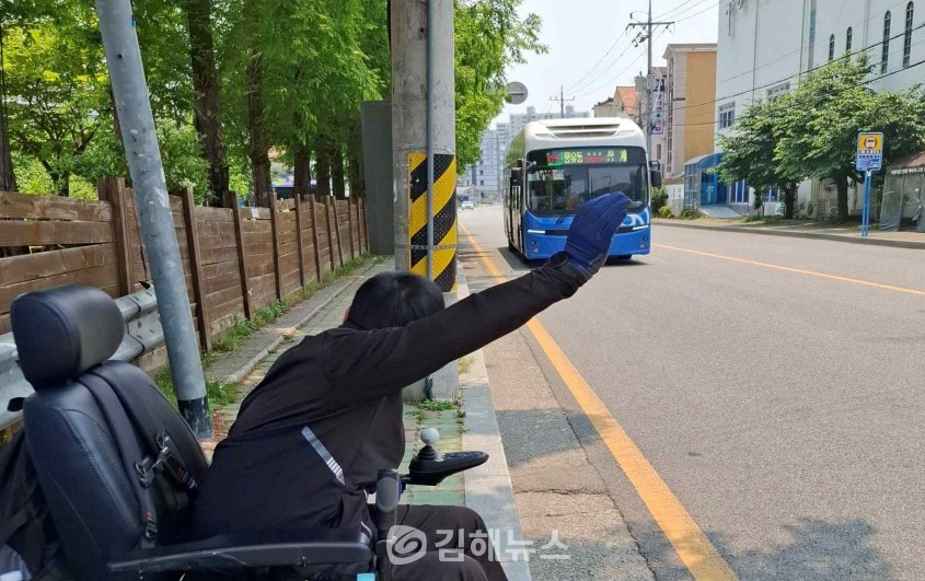 손을 들어 버스 승차의사를 밝히고 있는 한 장애인 / 김해장애인인권센터
